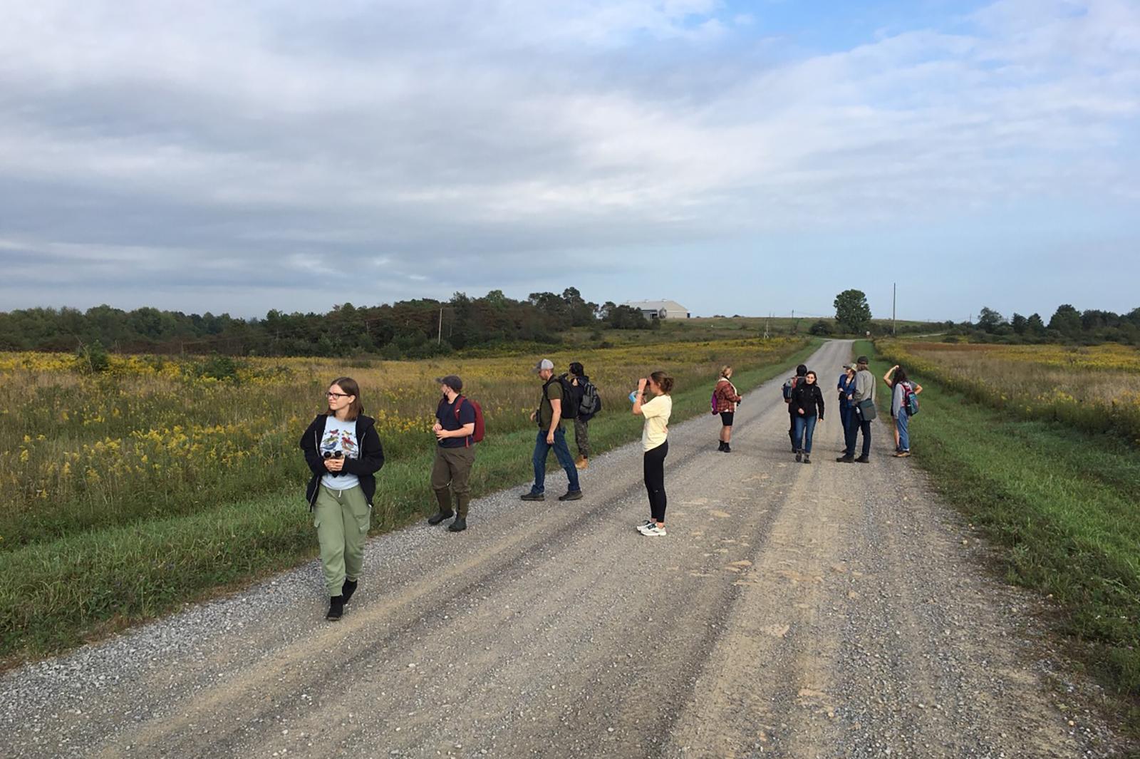 Students are in a field, observing birds for an ornithology class